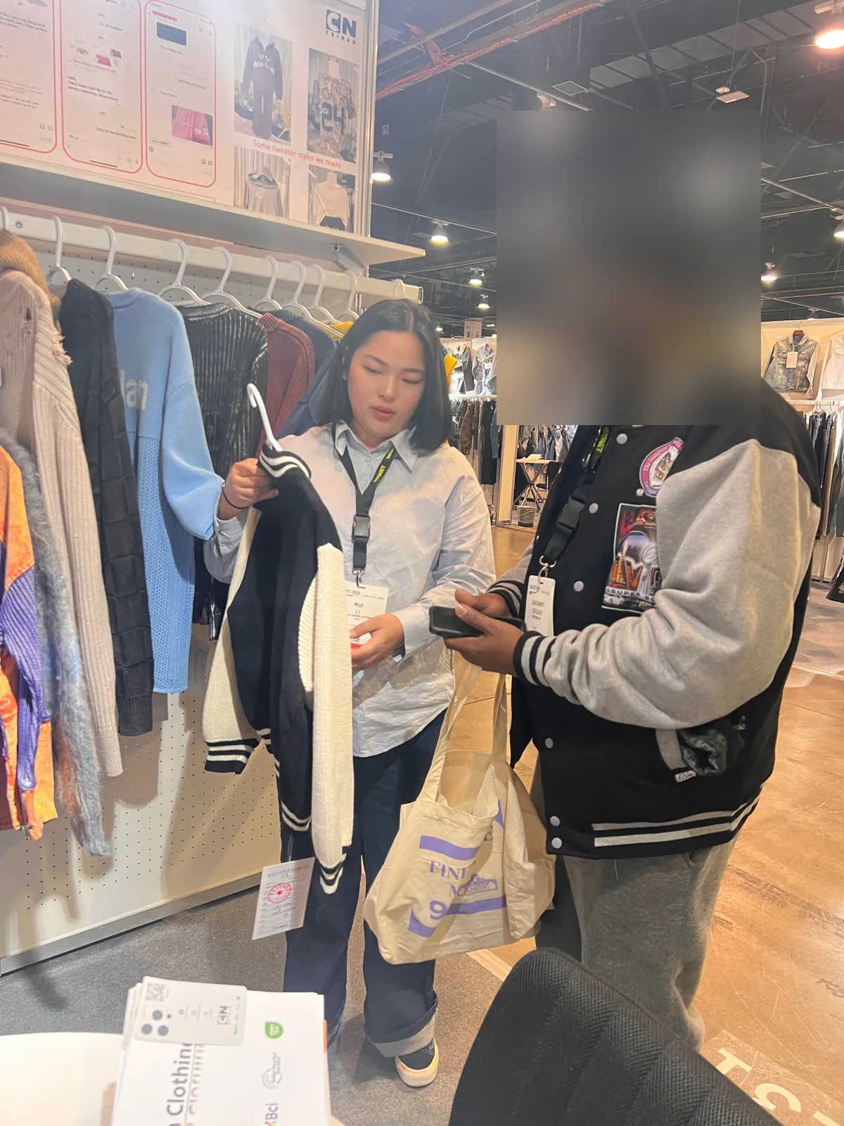 Buyer reviewing a knit varsity jacket sample at the Cainan booth