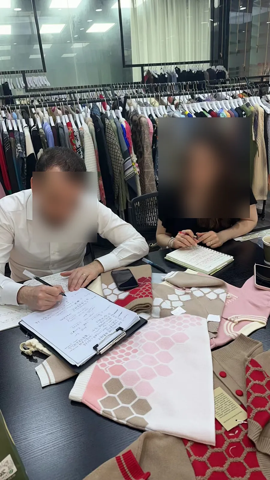 Buyers confirming order details and knit swatches at Cainan Clothing