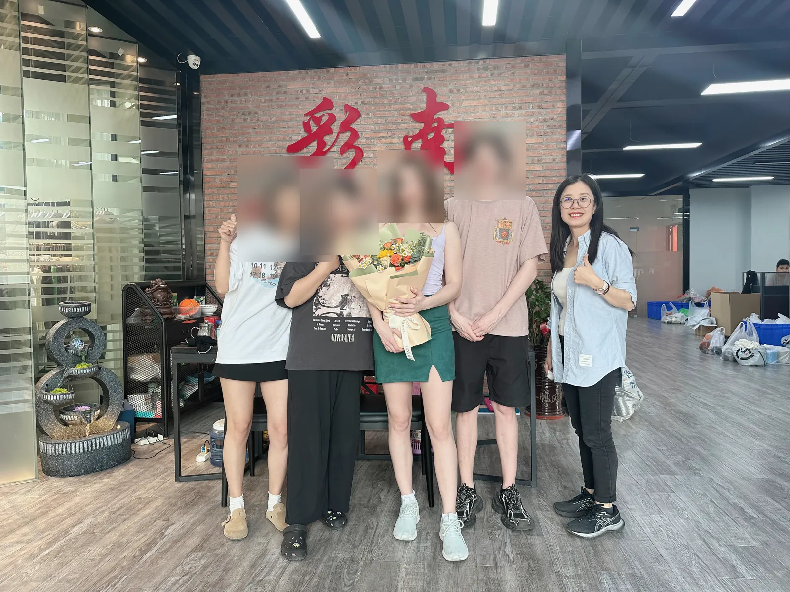 Customer visit group photo at the Cainan Clothing logo wall