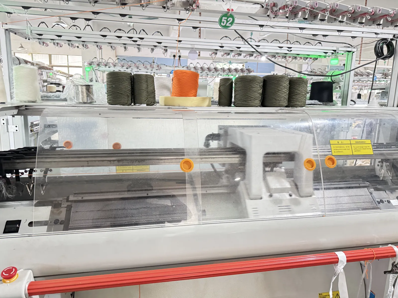 Checked yarn cones loaded on a flat knitting machine at Cainan