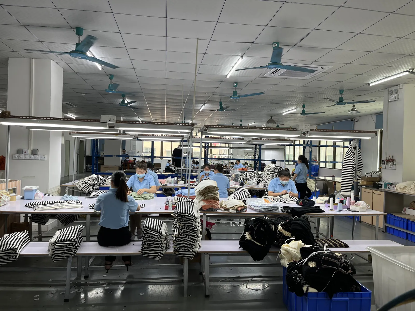 Workers linking and hand finishing knitted sweater panels
