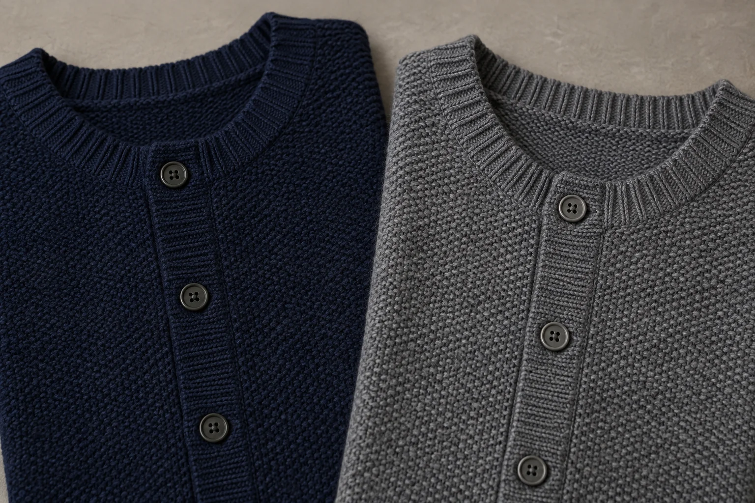 Close view of navy and gray knitted cardigan fronts with button plackets.