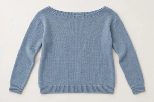 Blue knitted sweater laid flat with a wide boat neckline and long sleeves
