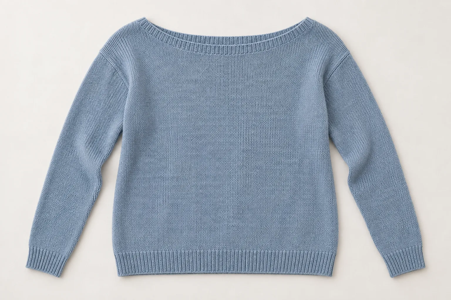 Blue knitted sweater laid flat with a wide boat neckline and long sleeves