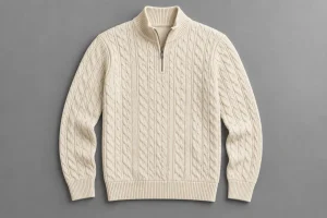 Cream cable-knit quarter-zip sweater laid flat with a short straight zipper