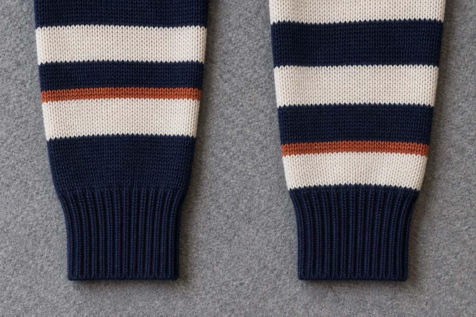 Two navy and cream striped sleeve ends with rust bands at different heights on grey felt